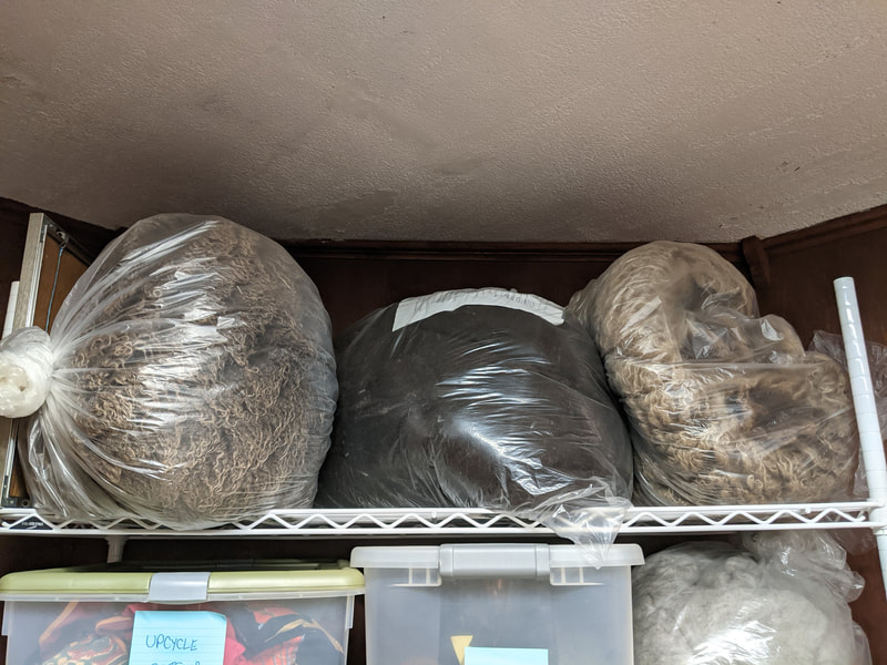Three bags of dirty fleece placed at the top of a shelving unit.