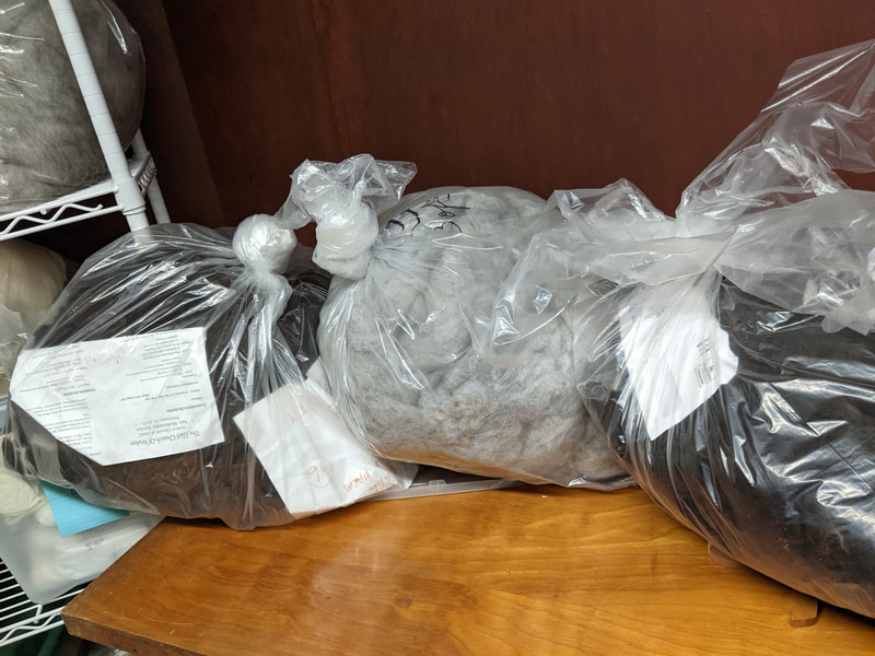 Three bags of cleaned, combed fleece sit on top of a table.